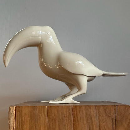 A bird sculpture of a toucan sprayed in a beige shiny gloss finish