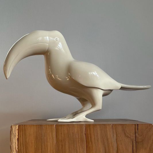 A bird sculpture of a toucan sprayed in a beige shiny gloss finish
