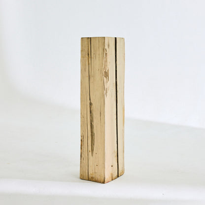 A tall thin solid wooden side table rustic in style.