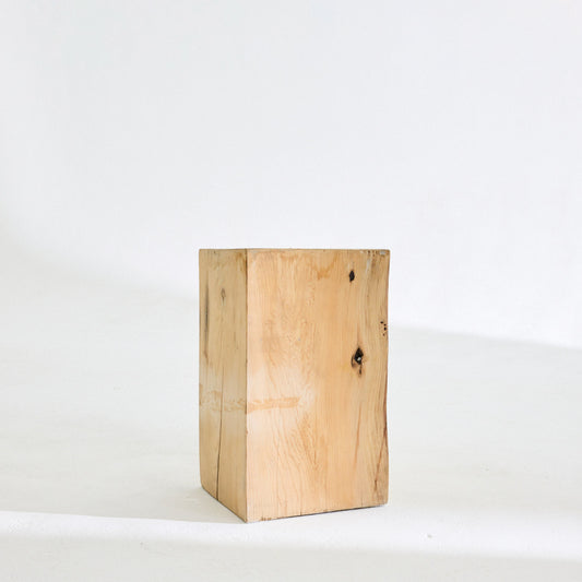 A pale solid wood block side table